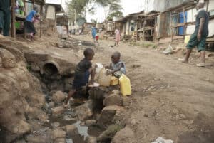 boys take water on a street of kibera, nairobi, kenya.