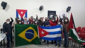 Participantes do evento segurando bandeiras do Brasil, Cuba e da Palestina. Créditos Coletivo José Martí de Solidariedade à Cuba e aos Povos em Luta