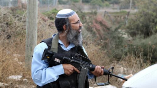 Colono israelense segurando uma arma de fogo.